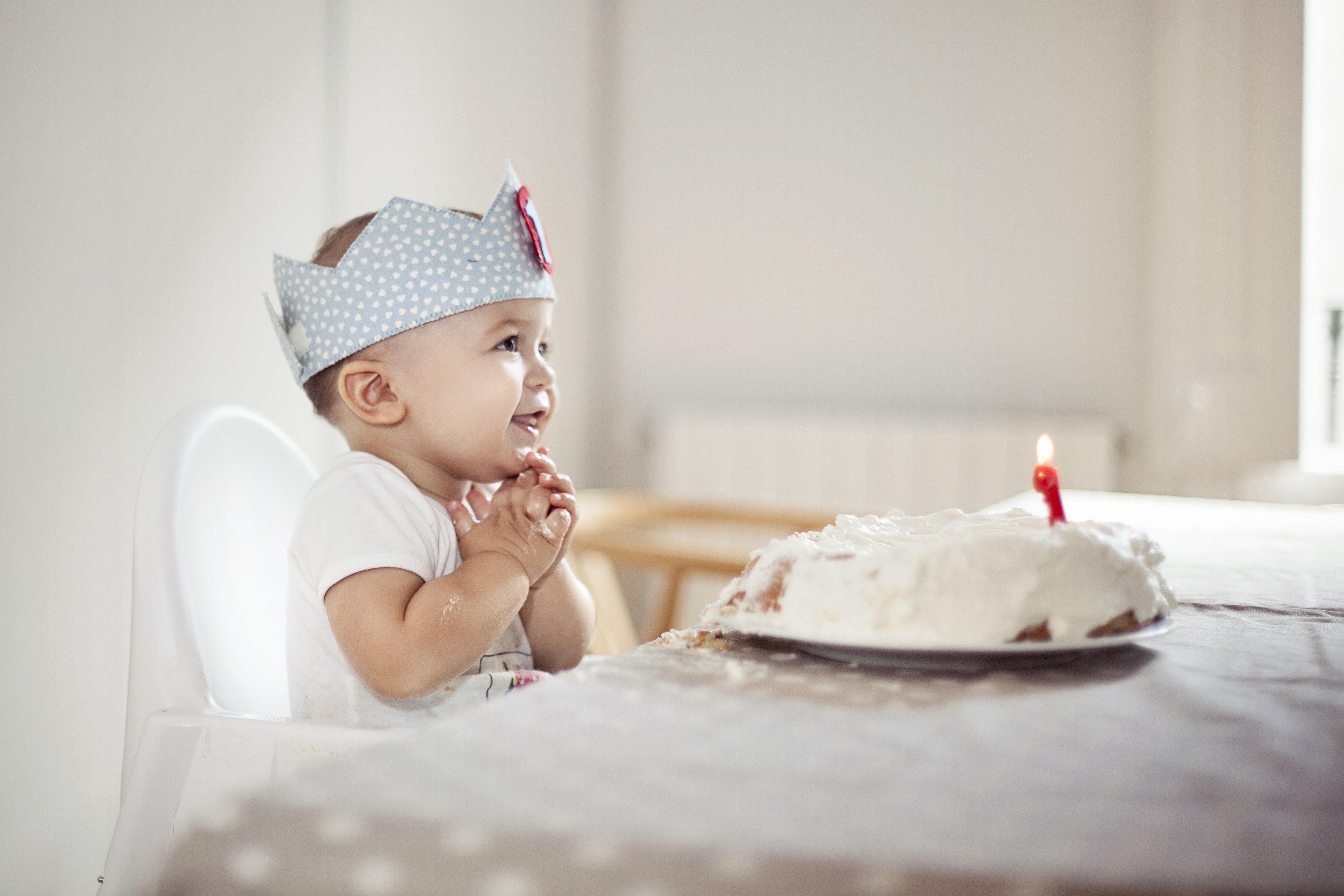 baby on his first birthday blowing out candle on birthday cake