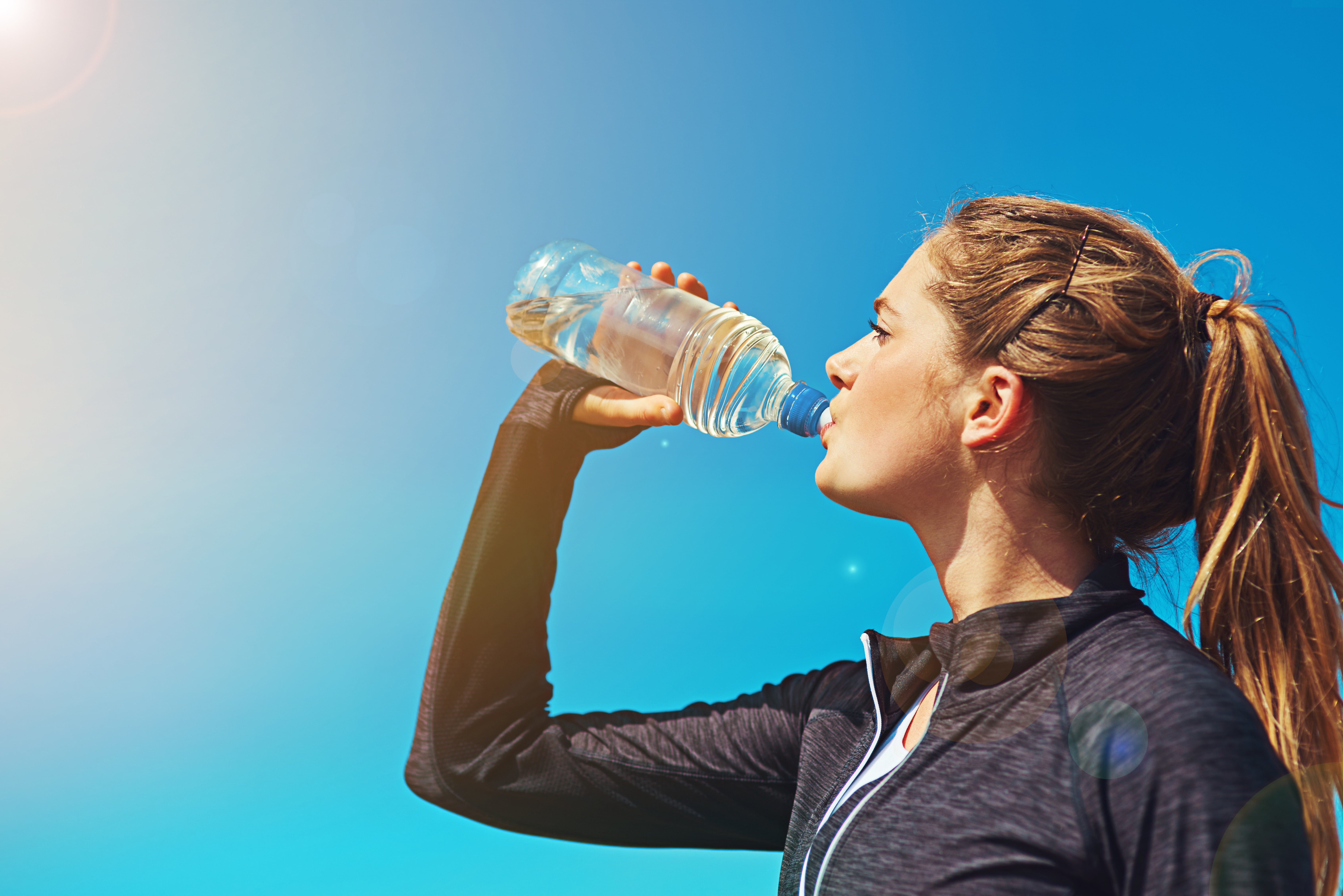 young woman drinking water in summer