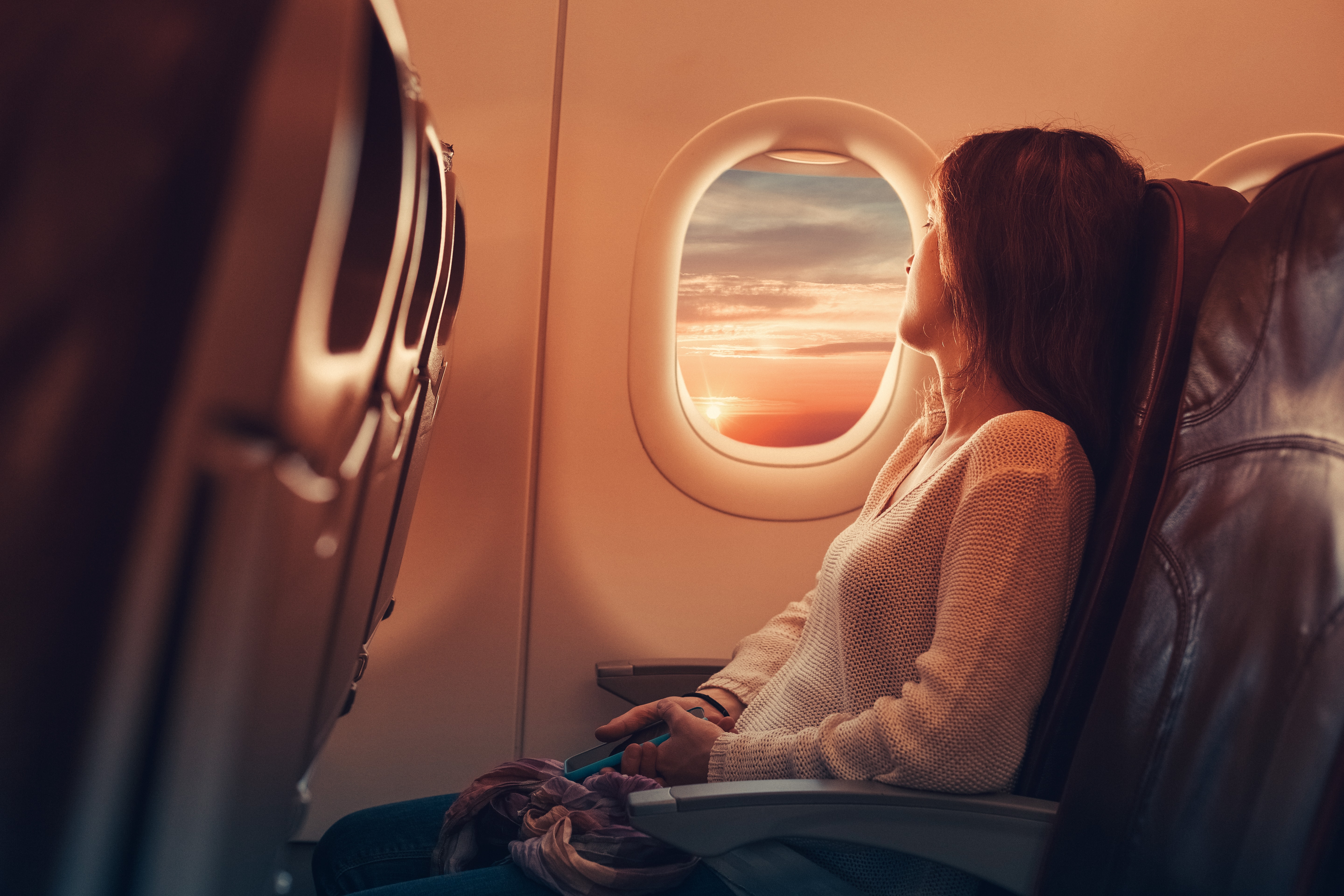 woman looking out airplane window flying